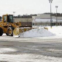 A large yellow earth mover plowing snow after a blizzard